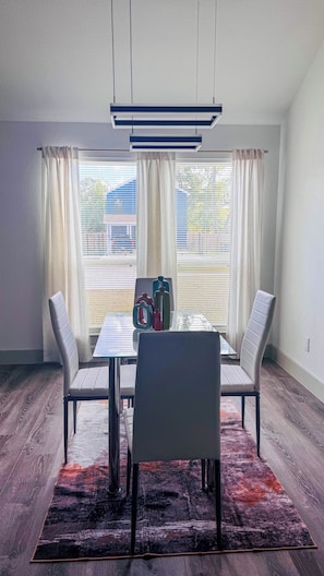 Un comedor con una mesa, sillas, un tapete y vistas a través del ventanal.