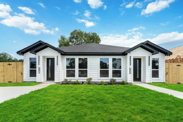 A two-story house with a symmetrical facade, white siding, and a dark roof. - Little Nyssa Home Away From Home (Houston)