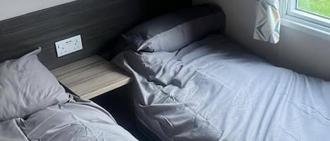 A bedroom with two single beds, a nightstand, and a window with curtains.