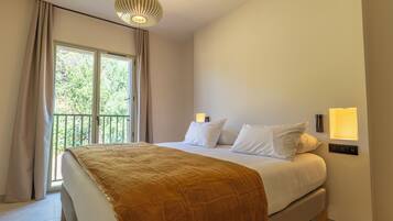 Une chambre à coucher avec un lit, des rideaux, une fenêtre et un luminaire fixé au mur.