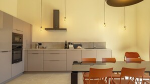 Una cocina moderna con comedor, que incluye horno empotrado, microondas y pileta de acero inoxidable.