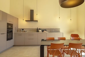 A modern kitchen with a dining area, featuring a built-in oven, microwave, and a stainless steel sink.