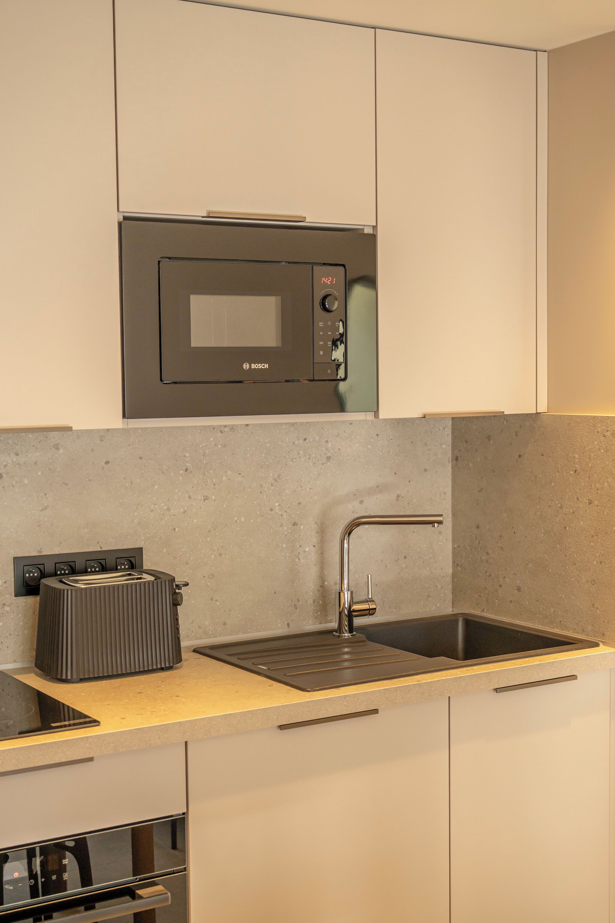 Een moderne keuken met een Bosch magnetron, een roestvrijstalen spoelbak en een inbouwoven.