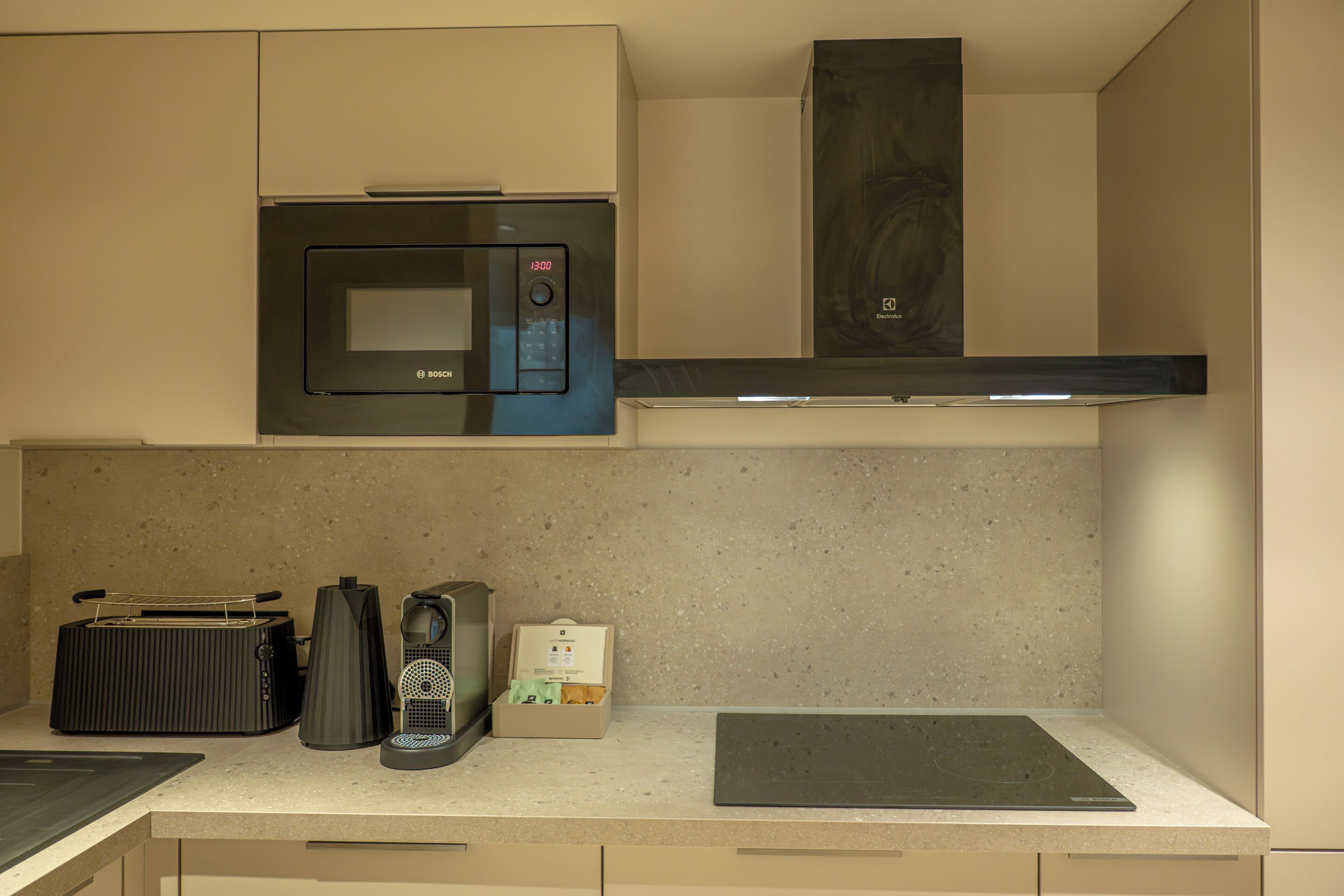 Een kitchenette met een magnetron, espressoapparaat en een broodrooster.