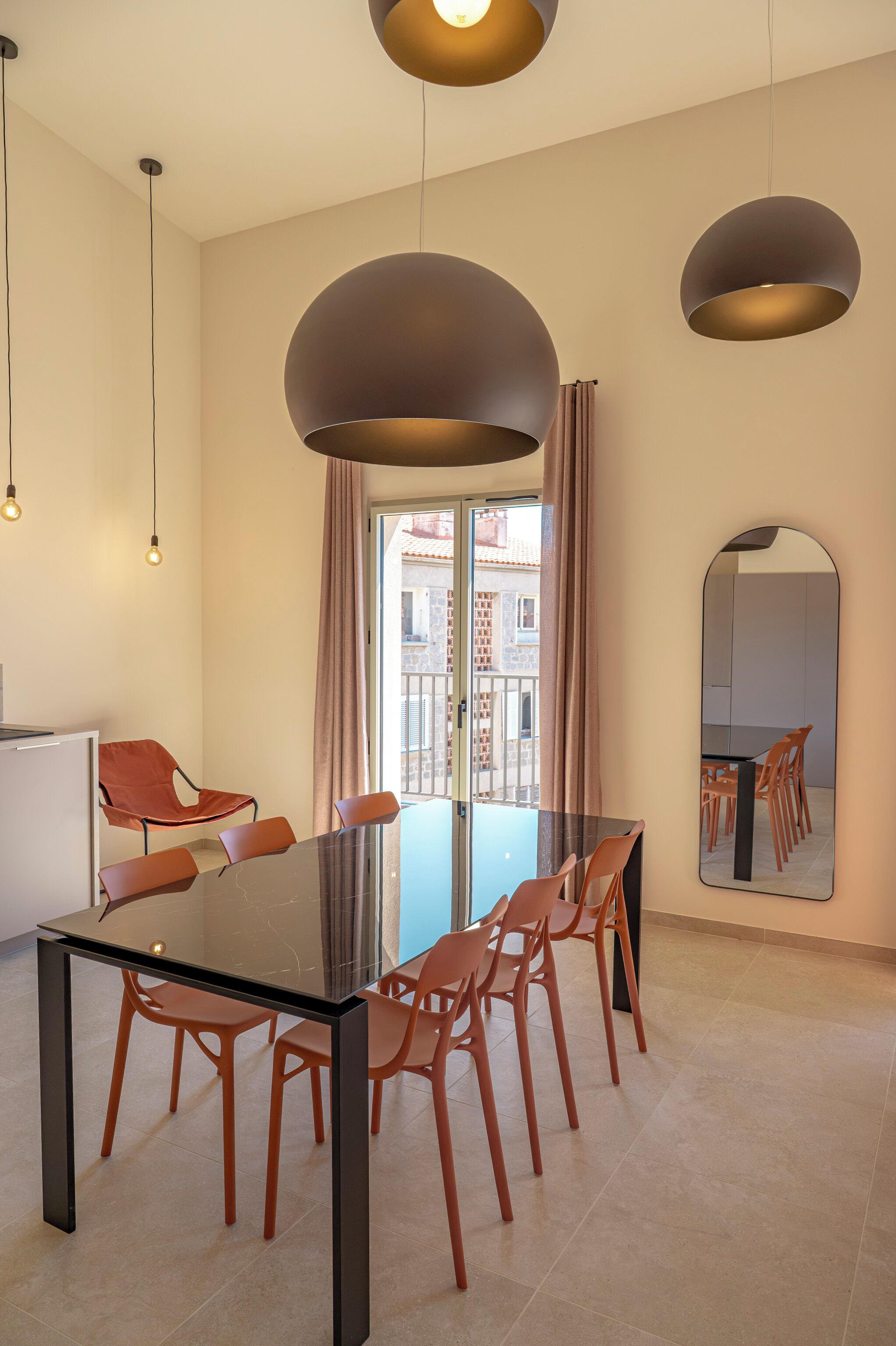 A modern dining area with a glass table, wooden chairs, and pendant lighting.