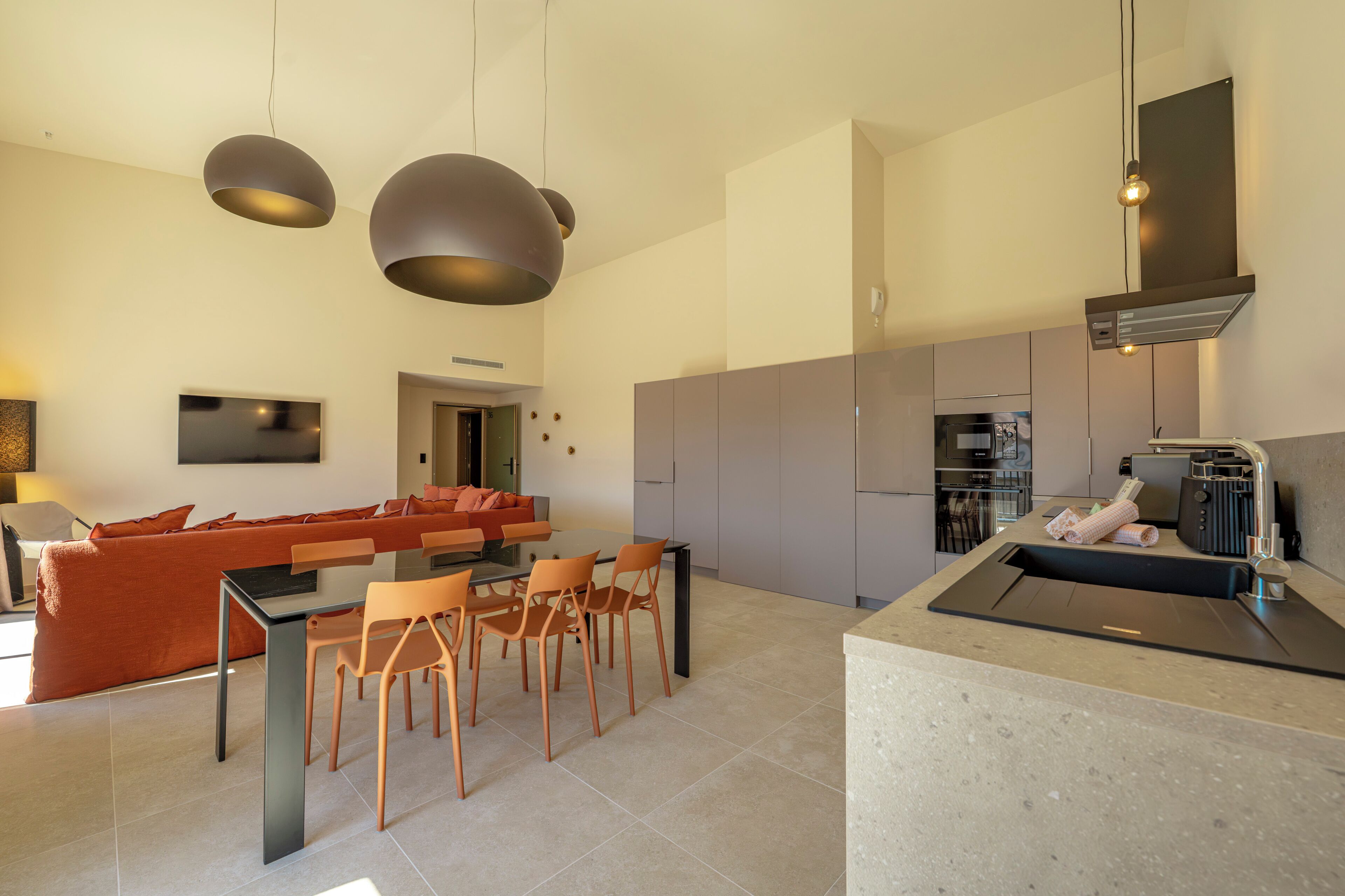 Una cocina moderna con horno integrado, cafetera y lavamanos.