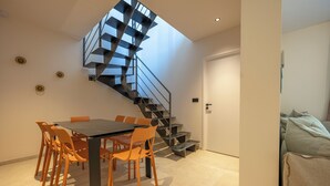 Un interior moderno con zona de comedor, escalera y sofá.