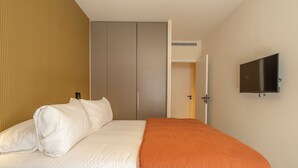 Una habitación de hotel con cama, armario, televisión y aire acondicionado.
