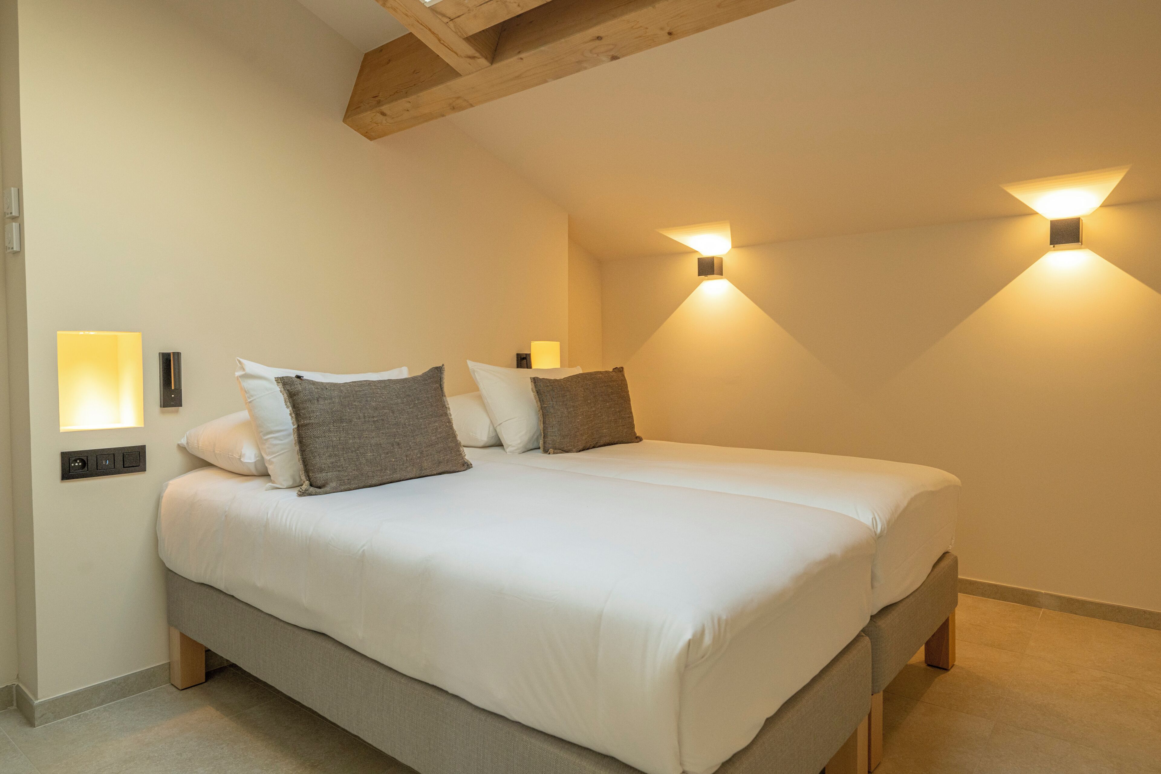 A bedroom with a bed, pillows, a nightstand, and two wall-mounted lights.