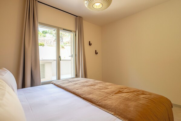 A bedroom with a bed, a window, and a door.