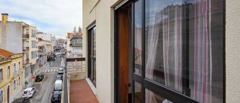 A narrow balcony with a view of a street and buildings.