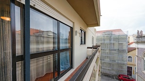 A building with large windows, a balcony, and a red car parked in front. - Fort Beach Apartment (Figueira da Foz)