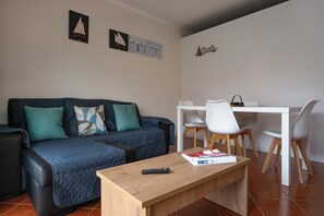 A living room with a sofa, a coffee table, and a dining area with chairs and a table.