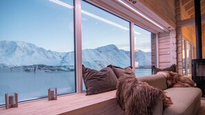 A cozy cabin interior with a large window overlooking a snowy mountain landscape.