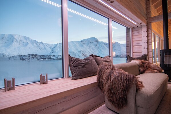 A cozy cabin interior with a large window overlooking a snowy mountain landscape.