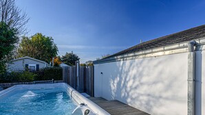 Una piscina con muelle de madera y pared blanca.