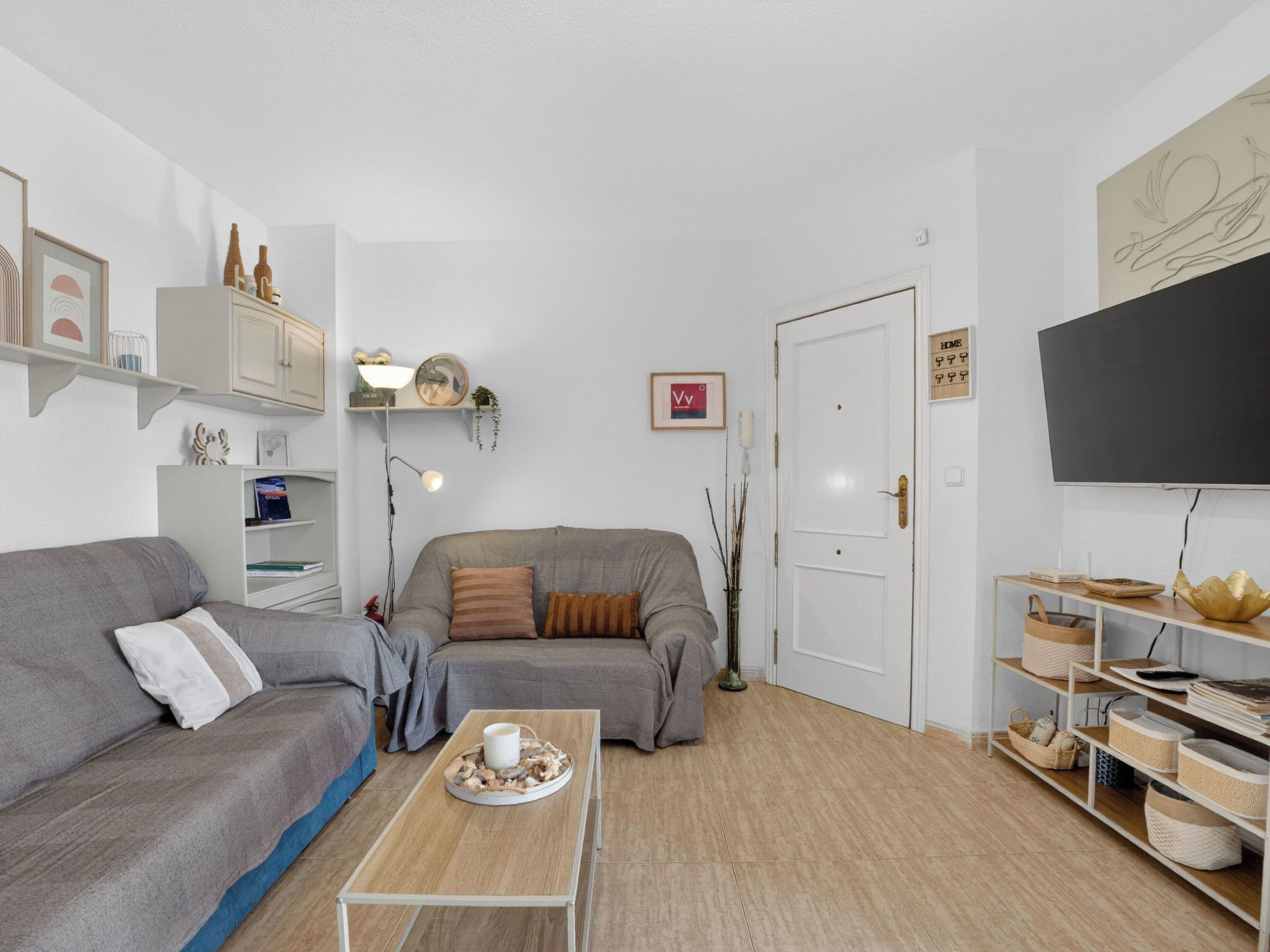 A living room with a sofa, a coffee table, a TV, and a bookshelf.