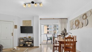 Un salon comprenant un canapé, une table basse, un téléviseur et un coin repas avec des chaises et une table.