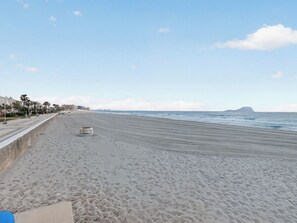 A beach with a concrete walkway, palm trees, and a distant island. - Los Ibicencos by Interhome (La Manga del Mar Menor)