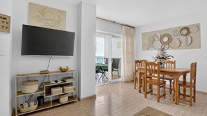 Un salon équipé d’un téléviseur à écran plat, d’une table à manger en bois, de chaises et d’une table basse.