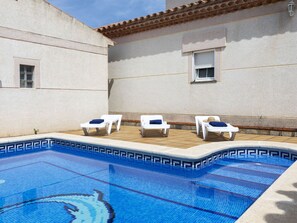 A swimming pool with four sun loungers, a tiled deck, and a building with a tiled roof and windows. - Vacation home Isabel by Interhome (Miami Platja)