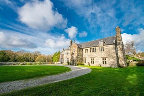 A large stone building with multiple windows and a well-maintained lawn.