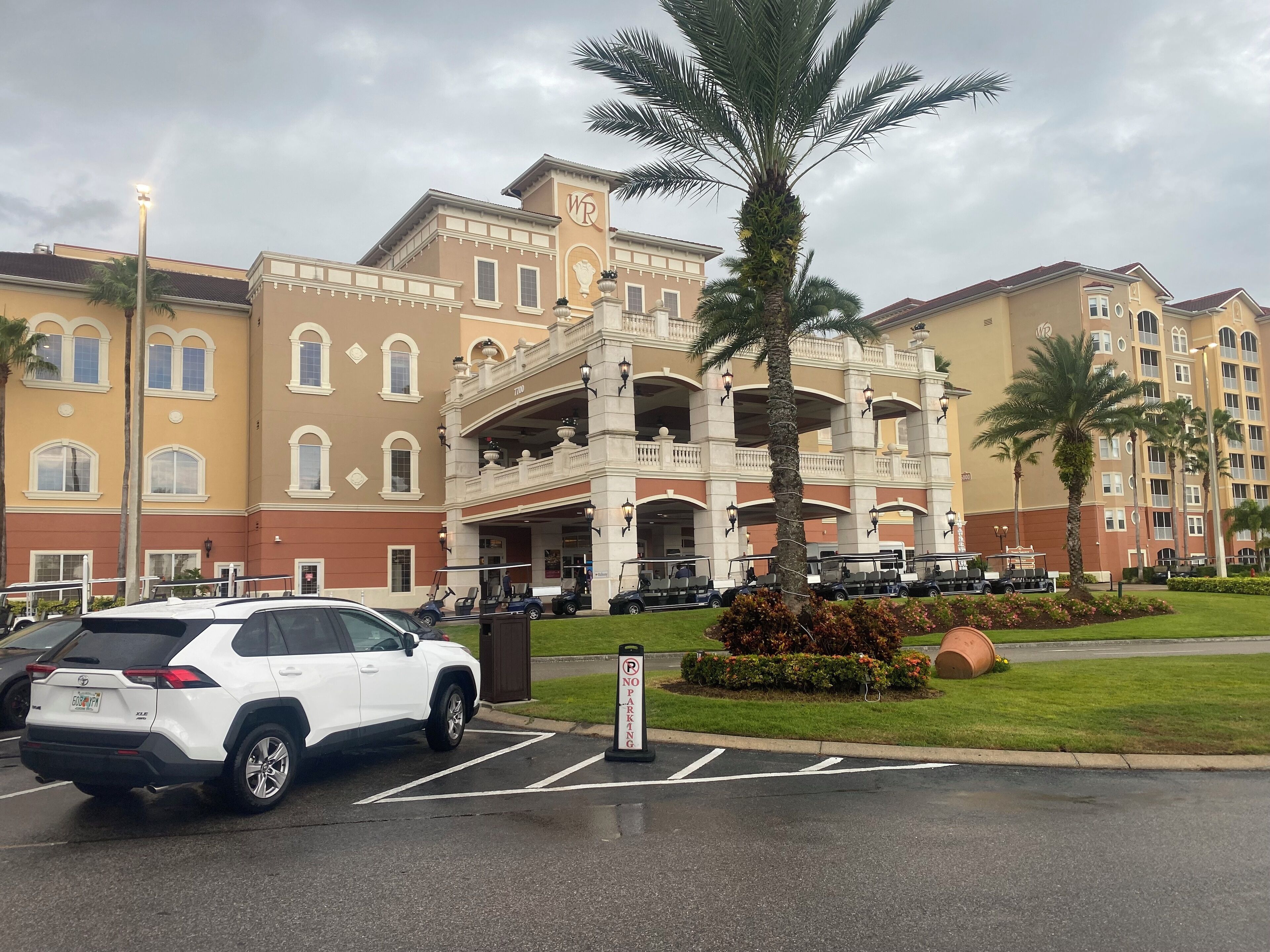A hotel with a central atrium, multiple floors, and a parking area with a white SUV.