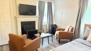 Ein Hotelzimmer mit Kamin, einem Bett, zwei Sesseln, einem kleinen Tisch und einem Fernseher.