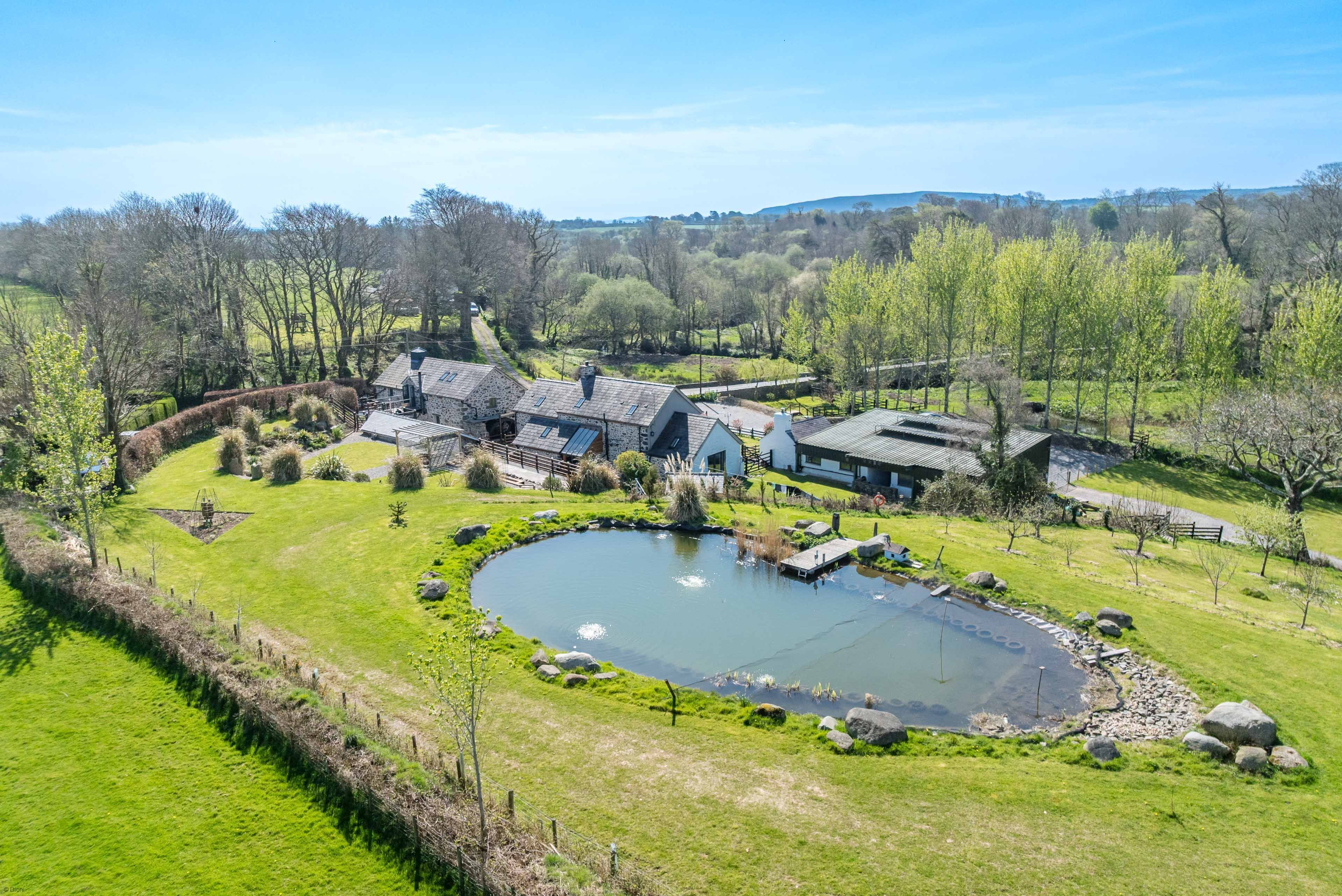 A large house with multiple rooms, a pond, and a well-maintained garden.