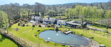 A large house with multiple rooms, a pond, and a well-maintained garden.