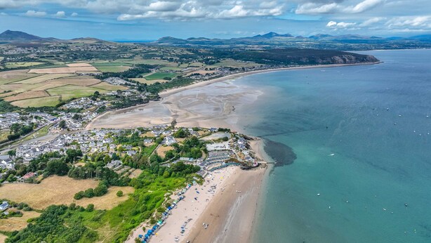 Vista aérea de un pueblo costero con playa, casas y campos.