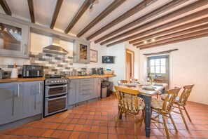 Une cuisine avec des meubles de couleur grise, un plafond en bois et un sol carrelé.