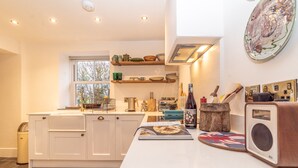 Una cocina moderna con armarios blancos, un ventanal y una encimera con diversos utensilios de cocina.