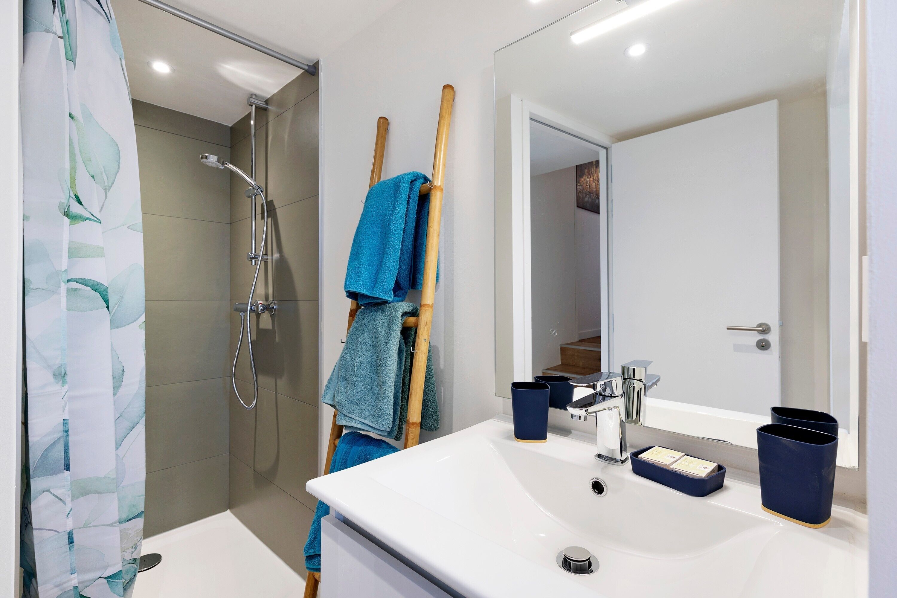 Un baño moderno con ducha, lavabo, espejo y toallero.