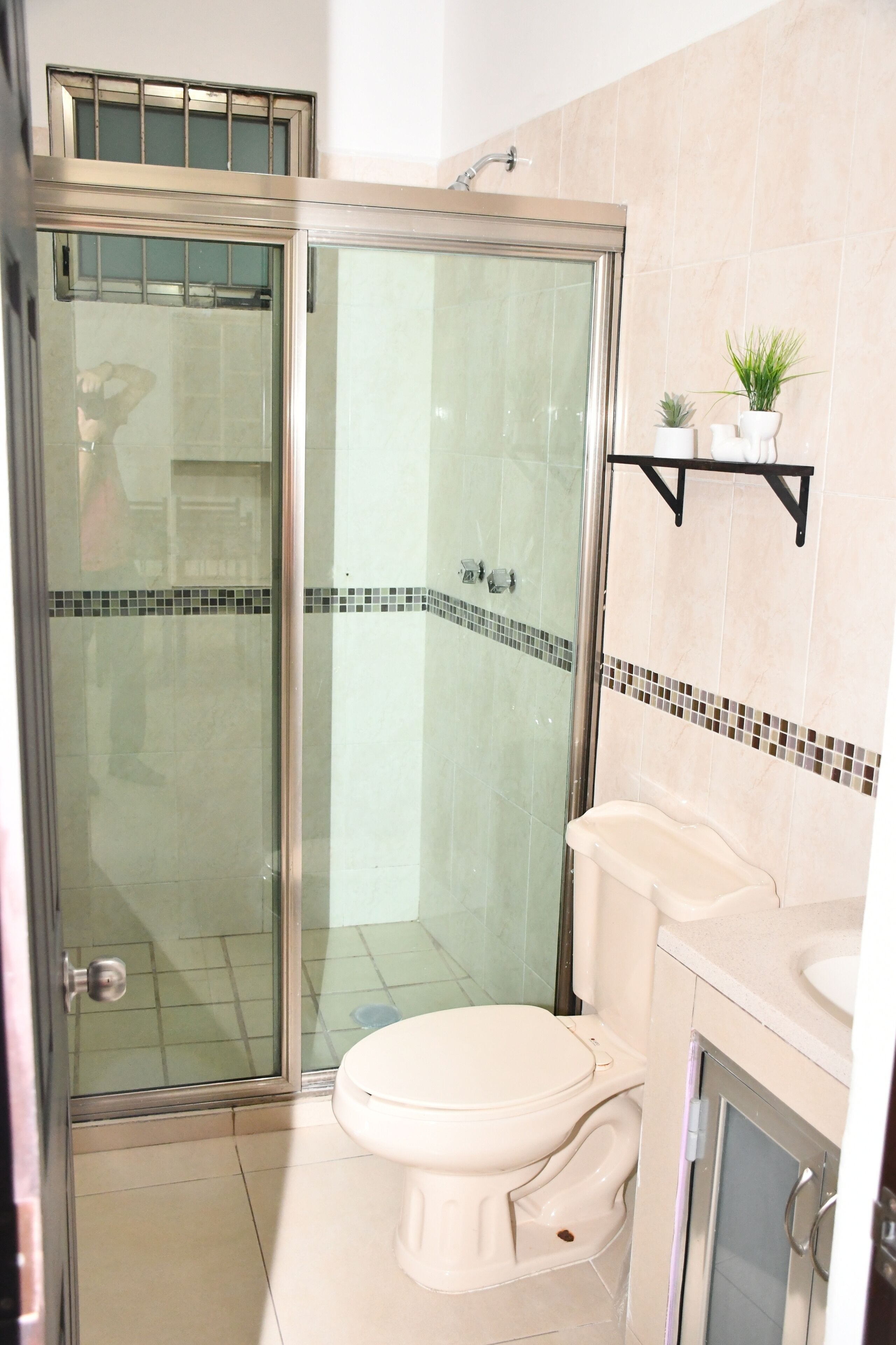 A bathroom with a glass-enclosed shower, a toilet, and a sink.