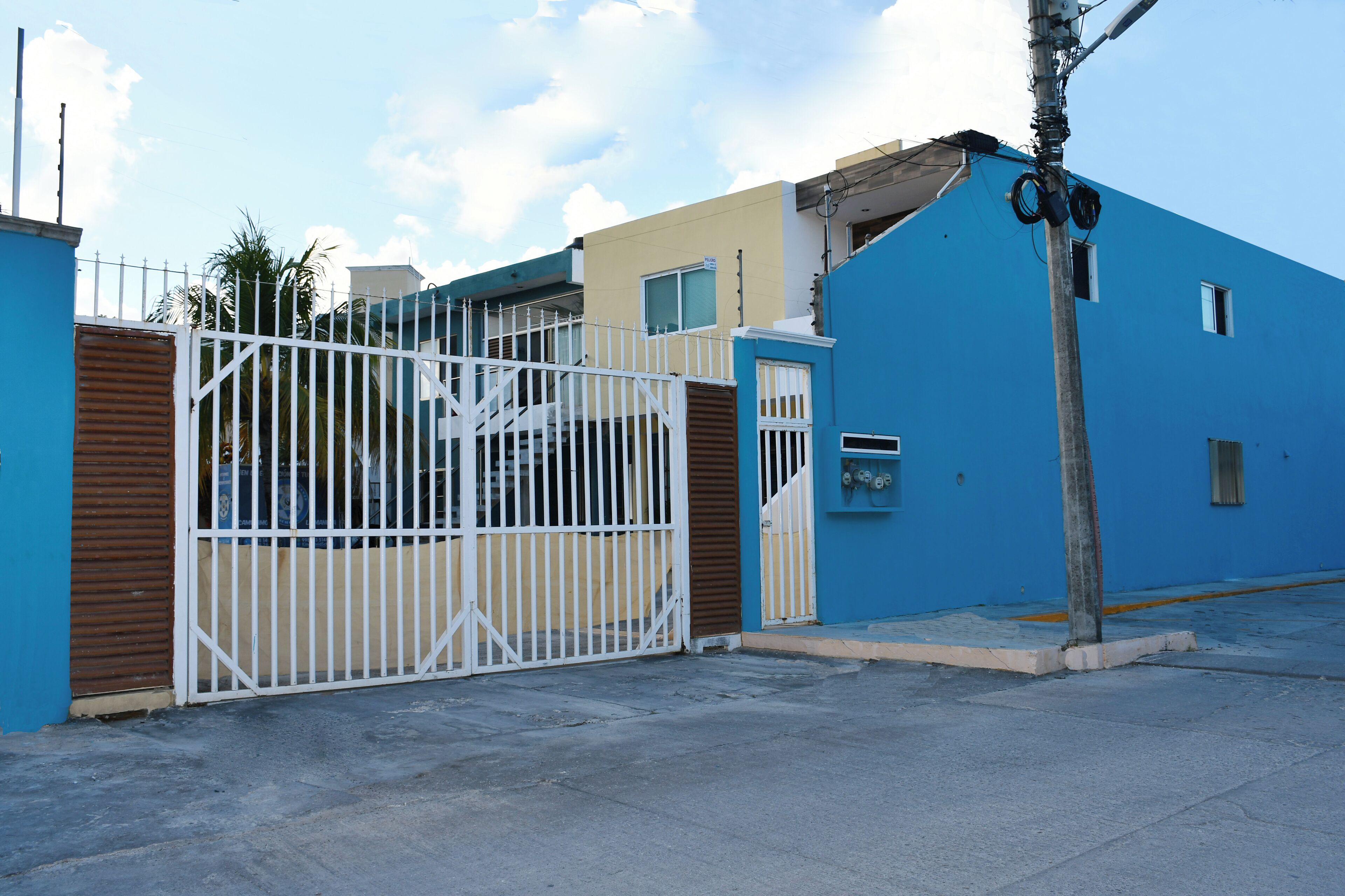 A gated residential area with a blue building, a white gate, and a utility pole.