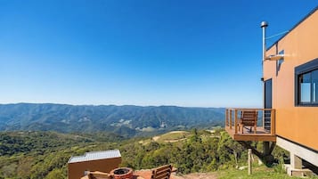 A modern building with a wooden deck and a view of a mountainous landscape.