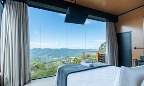 A bedroom with a large window, a bed, a wooden desk, and a view of the mountains. - Cabin With Panoramic View of the Sierra Vst043 (Anitapolis)