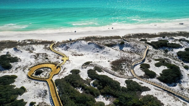 Eine Luftaufnahme einer Küstenregion mit einer gewundenen Straße und einem Strand.