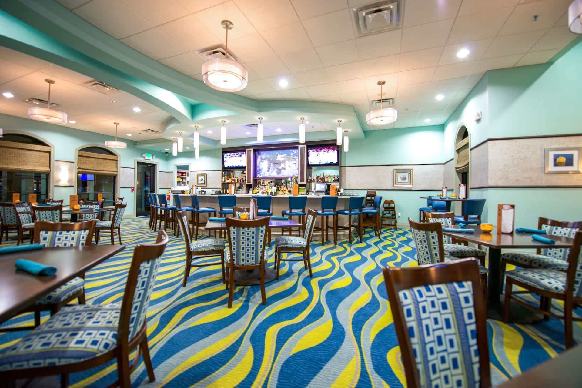 A hotel lobby with a bar area, seating arrangements, and a patterned carpet.