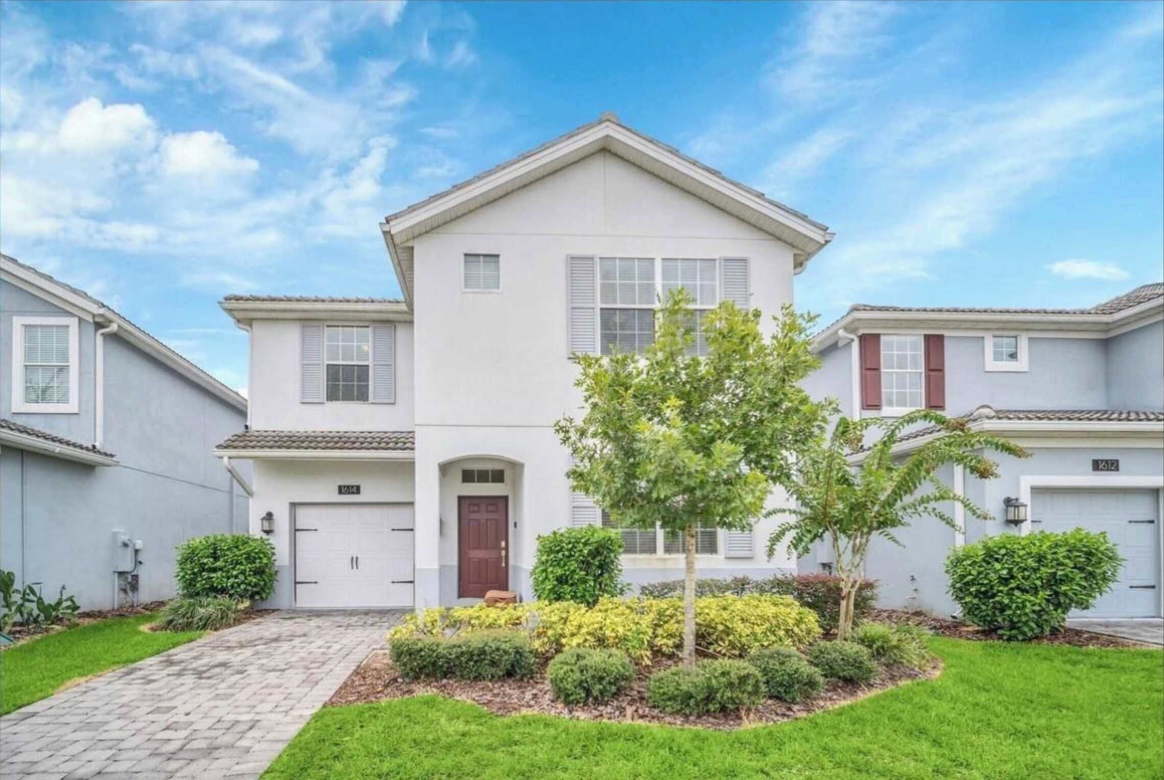 A two-story house with a front entrance, a driveway, and a well-maintained lawn.
