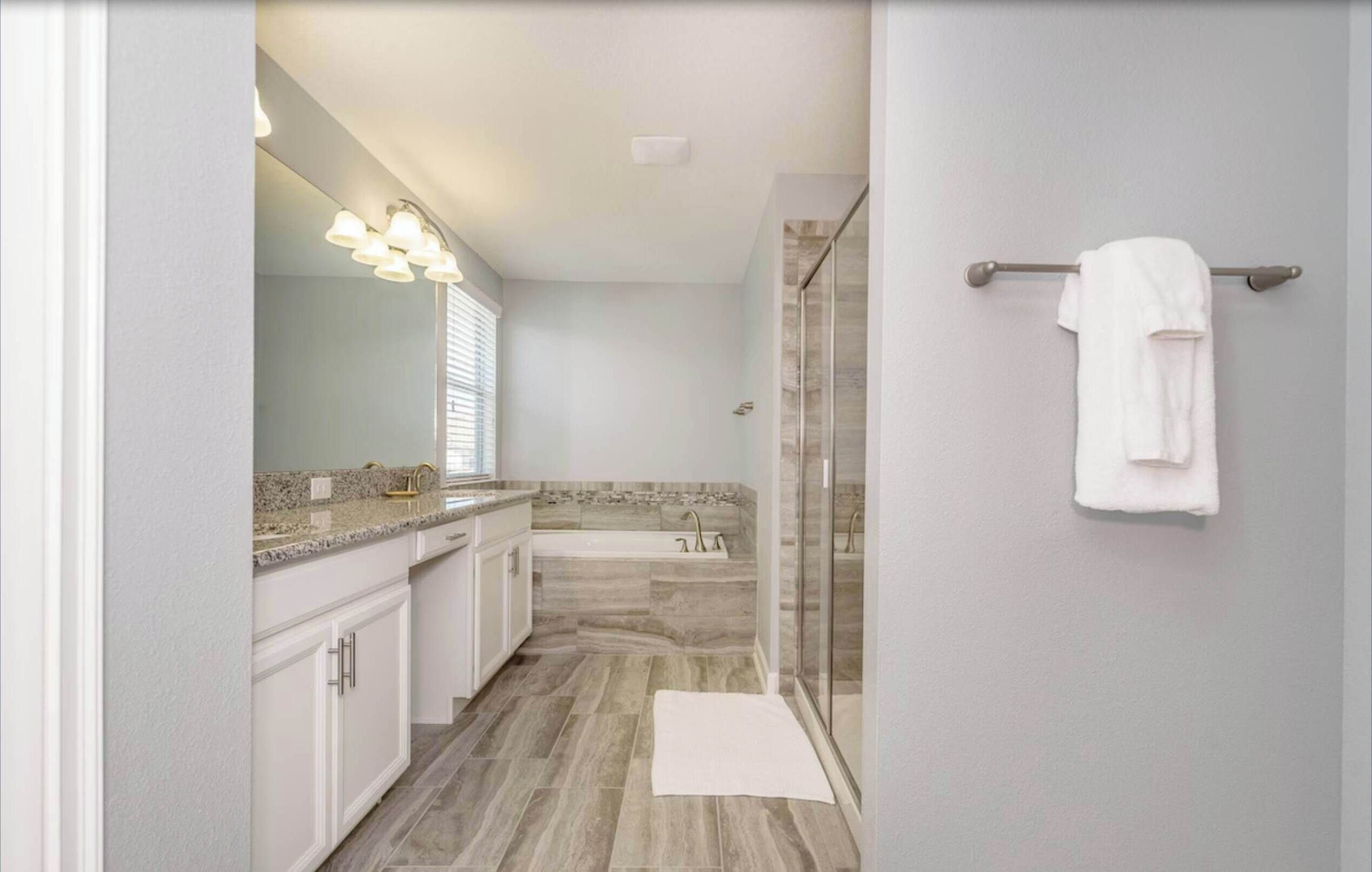 A modern bathroom with a vanity, a bathtub, and a shower area.