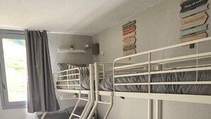 Ein Zimmer mit Etagenbetten, einem fenster mit Vorhängen und einer Wand mit Schildern.