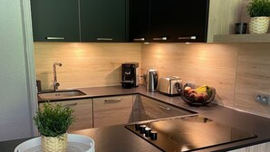 Eine moderne Küche mit dunklen Schränken, einer Holzarbeitsplatte, einem eingebauten Herd, einer Kaffeemaschine und einem Obstkorb.
