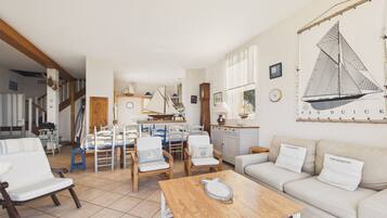 A spacious living area with a wooden coffee table, white sofas, and a sailboat painting on the wall.