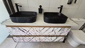 Een badkamer met twee zwarte marmeren wastafels, een witte marmeren wastafelmeubel en een toilet.