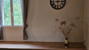 A room with a wooden bench, a wall clock, a window with curtains, and a vase with dried plants. - Cozy House for 4 in the Heart of the French Ardennes – Laundry, Bike Storage, Near Rocroi & Belgium (Gué-d'Hossus)