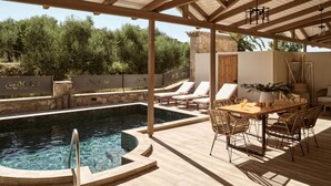 A pool area with a wooden deck, lounge chairs, and a table with chairs.