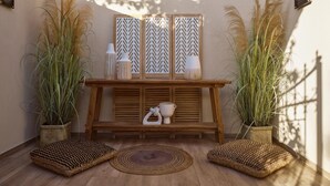 A sunlit patio area with a wooden table, decorative vases, and tall plants.