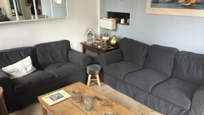 Ein Wohnzimmer mit zwei grauen Sofas, einem Holztisch und einem kleinen Hocker.